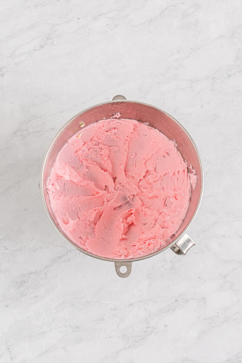 pink buttercream frosting for chocolate covered strawberry cheesecake in a stainless mixing bowl.