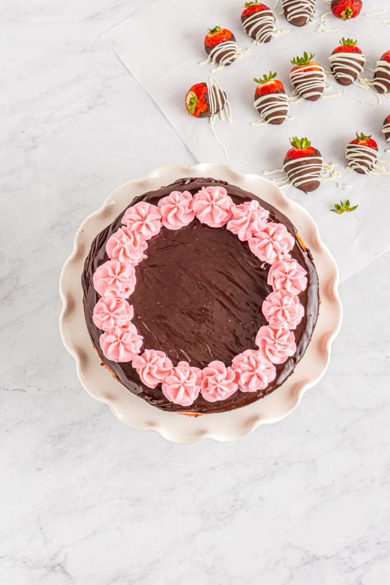 pink buttercream frosting piped onto chocolate covered strawberry cheesecake.