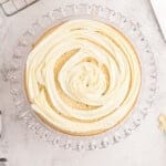 buttercream piped in a spiral on a layer of easy homemade wedding cake on a glass cake stand.