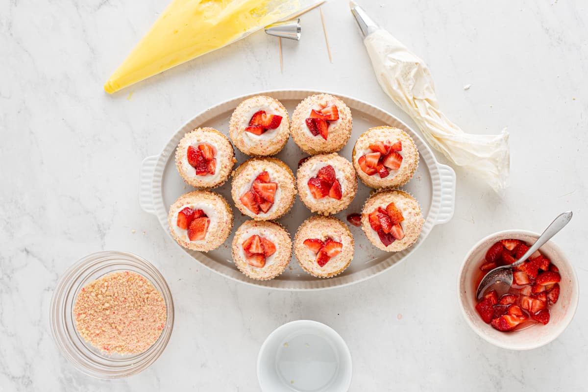 overhead view of 10 strawberry shortcake cupcakes on an oval serving tray.