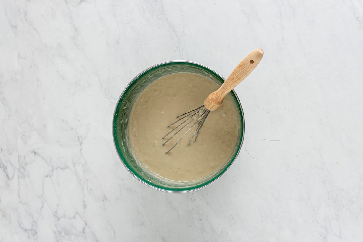 overhead view of whisked strawberry shortcake cupcake batter in a green bowl with a whisk.