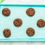 6 baked andes mint cookies on a blue baking sheet.