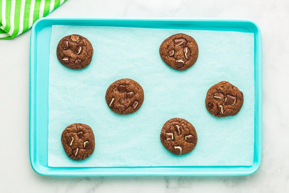 6 baked andes mint cookies on a blue baking sheet.