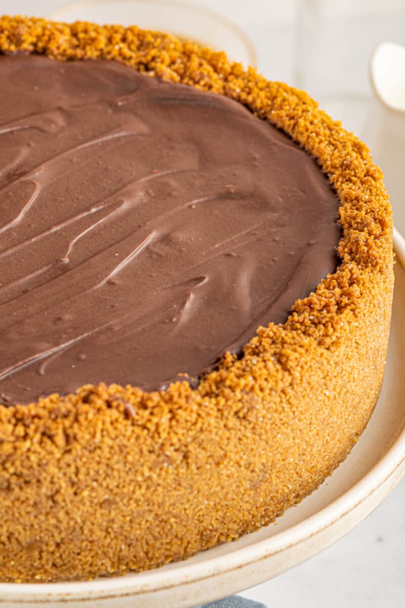 chocolate caramel cheesecake on a white cake stand.