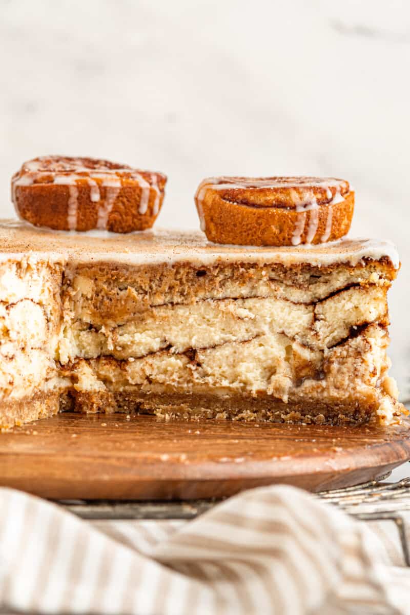 sliced cinnamon roll cheesecake on a wooden platter.