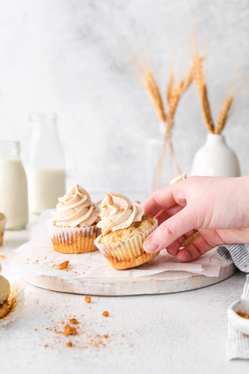 hand grabbing a cinnamon swirl cupcake from a marble serving platter.