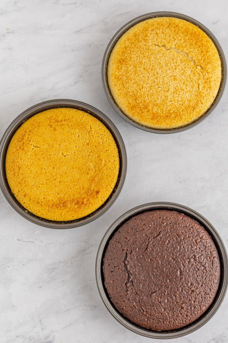 baked chocolate caramel and vanilla cakes in cake pans.
