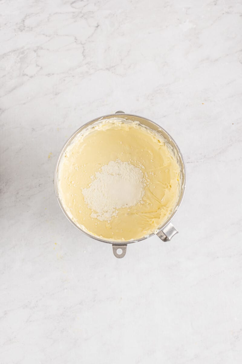 cornstarch and salt added to cinnamon roll cheesecake batter in a stainless mixing bowl.