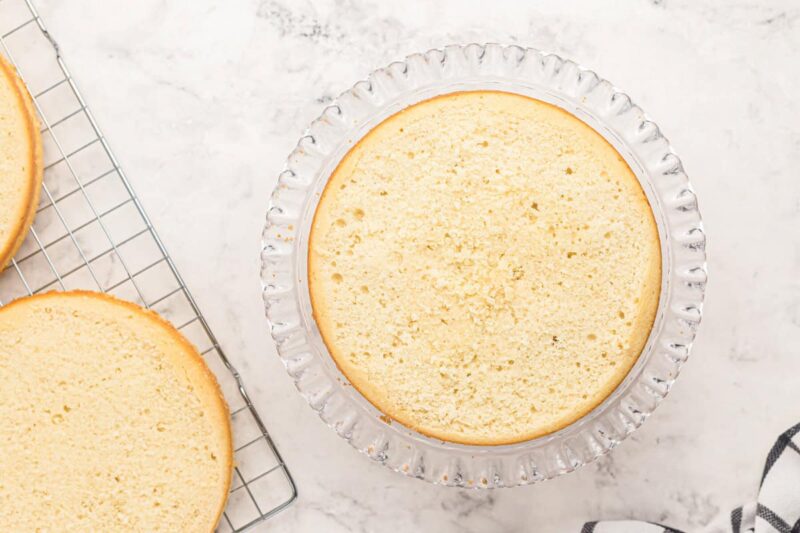 a leveled wedding cake layer on a glass cake stand.