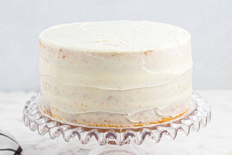 crumb-coated 3-layer wedding cake on a glass cake stand.