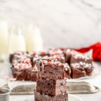 profile view of 3 stacked peppermint brownies on a white plate.