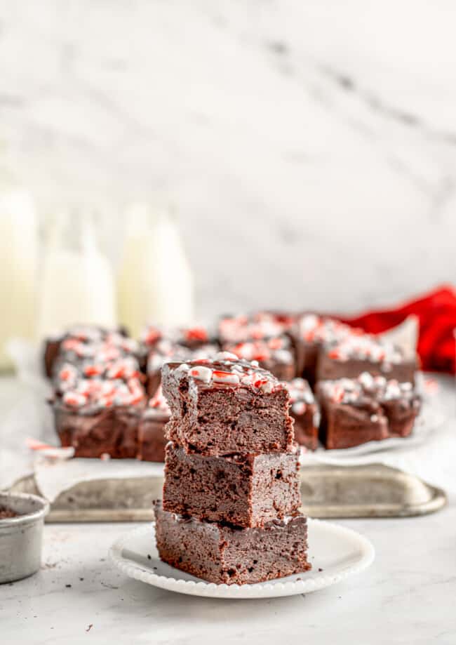 profile view of 3 stacked peppermint brownies on a white plate.