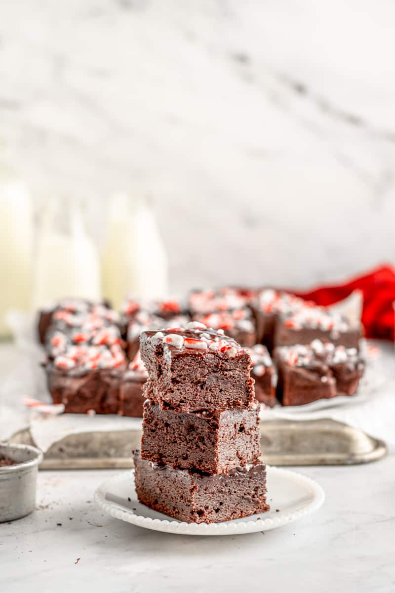 profile view of 3 stacked peppermint brownies on a white plate.