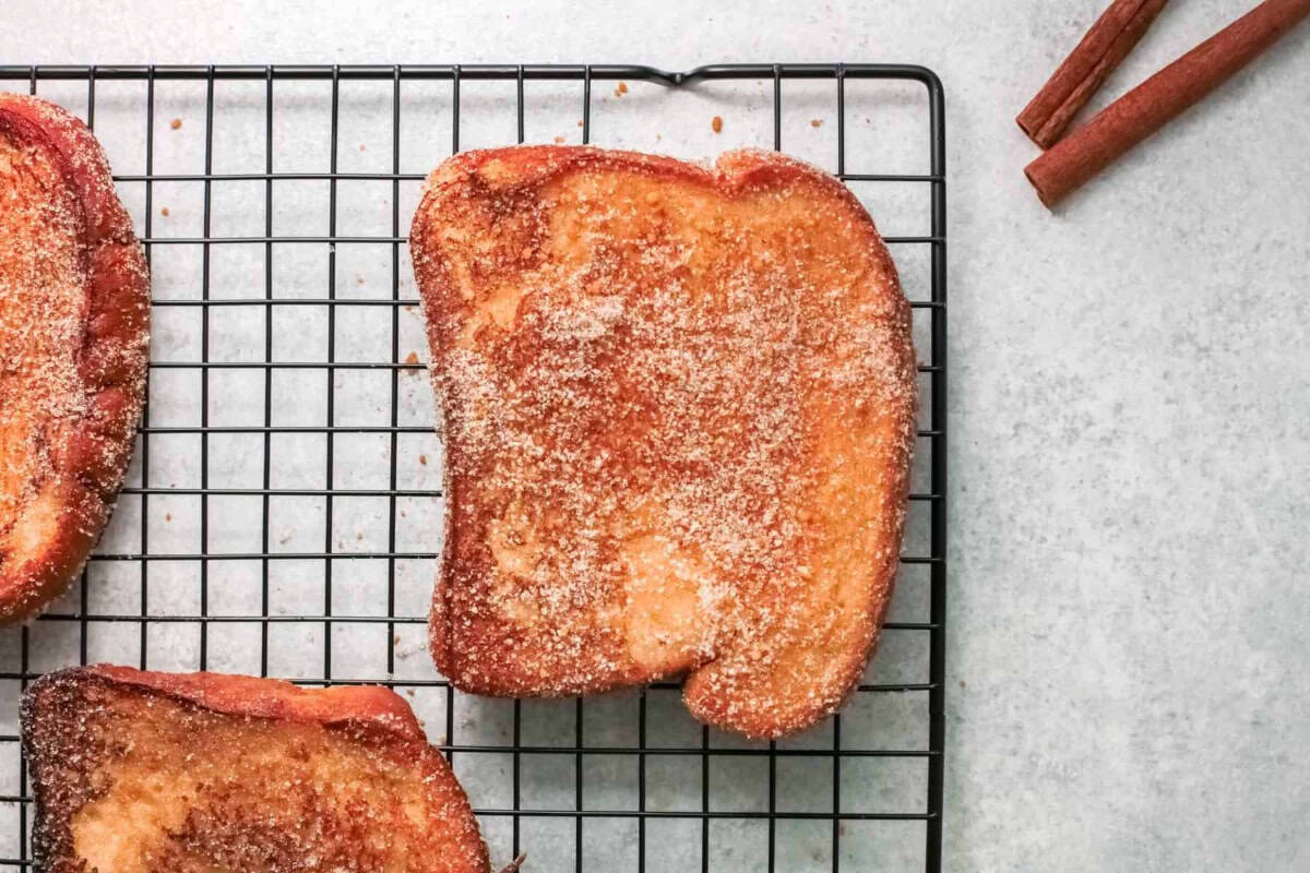 partial overhead view of a slice of cinnamon sugar french toast on a wire rack.