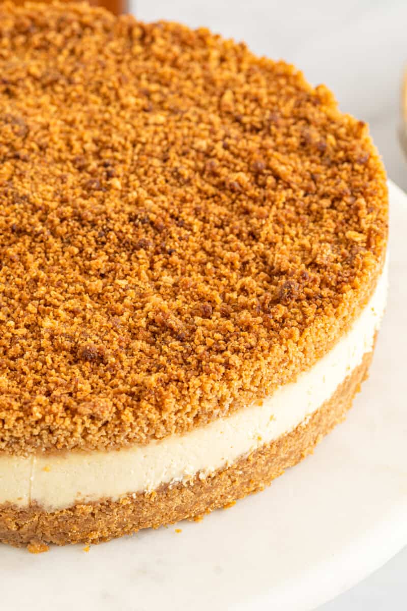 close up of double crust cheesecake on a white cake stand.