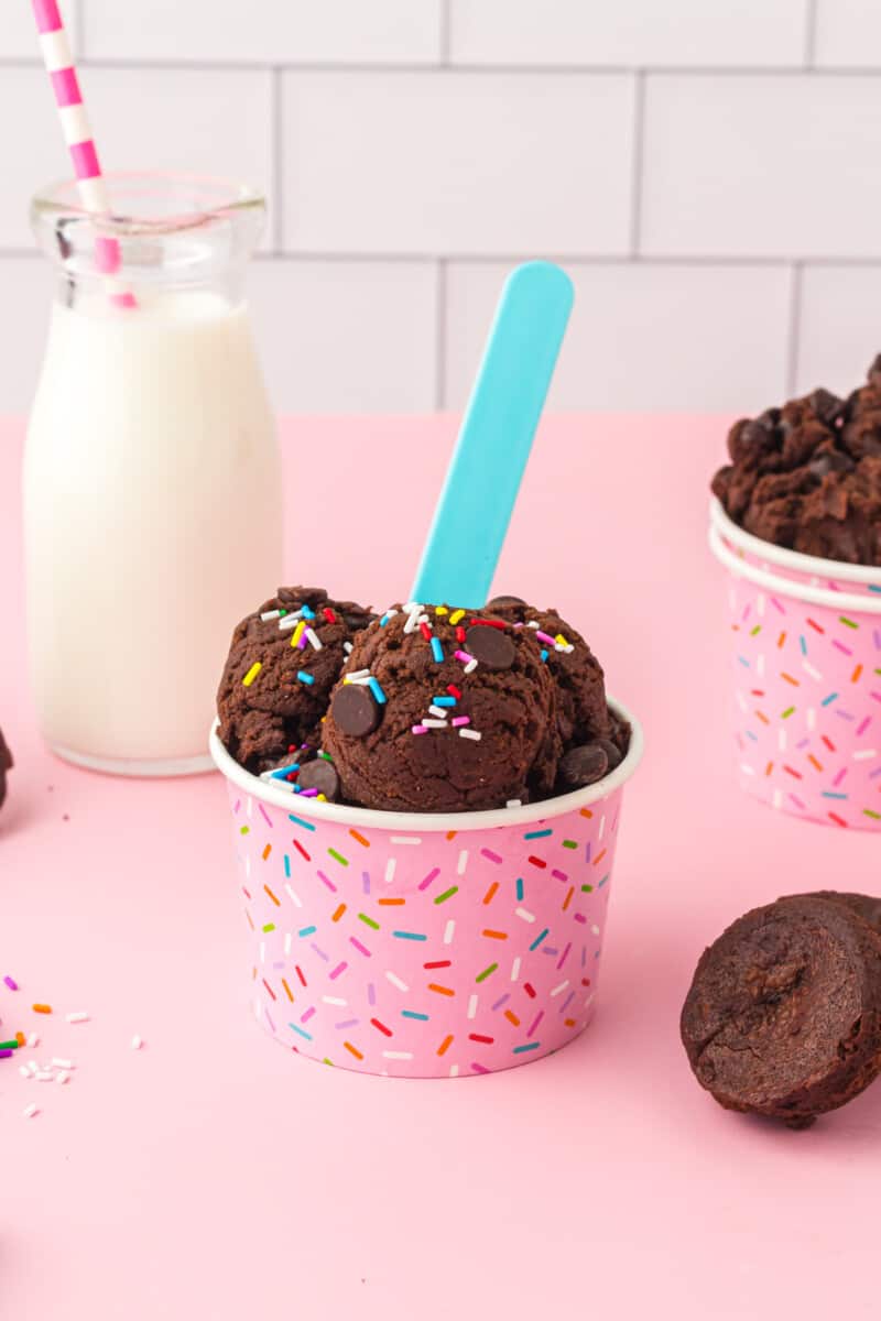edible brownie batter in a pink sprinkle cup with a blue spoon.