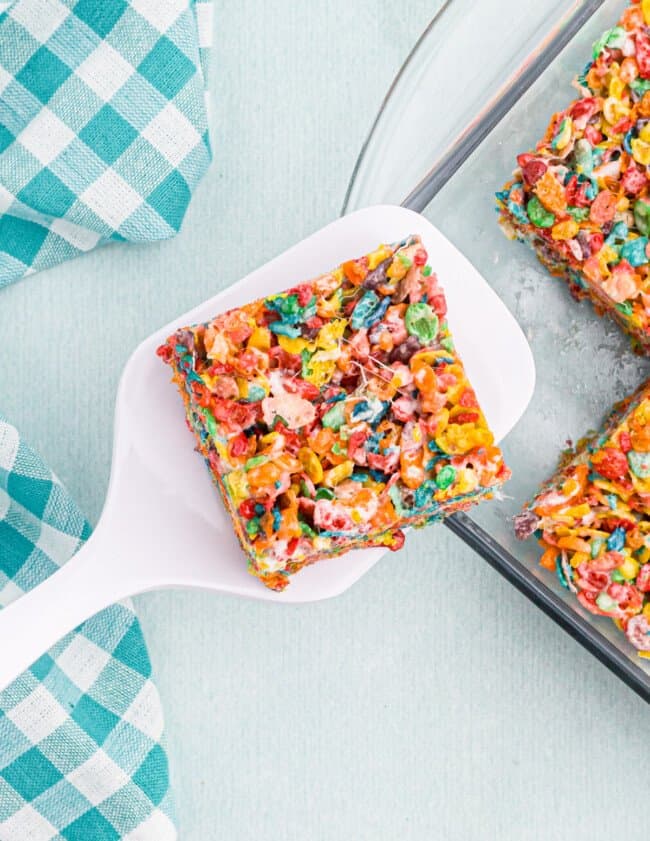 overhead view of a sliced fruity pebbles treat on a white spatula.