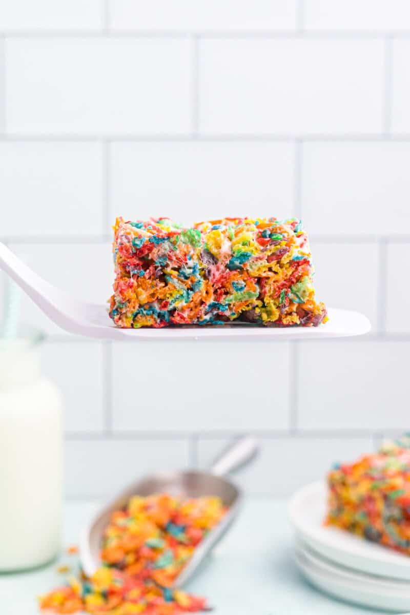 profile view of a sliced fruity pebbles treat on a white spatula.