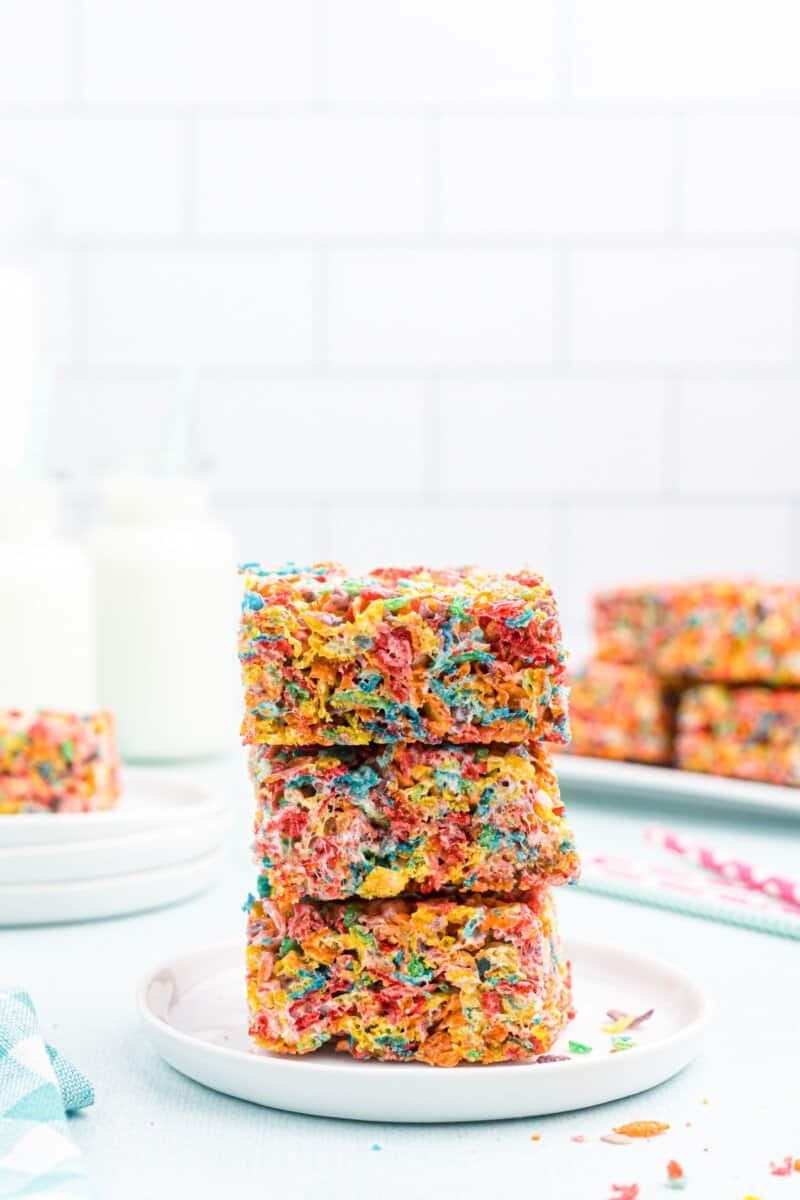 profile view of 3 stacked fruity pebbles treats on a white plate.