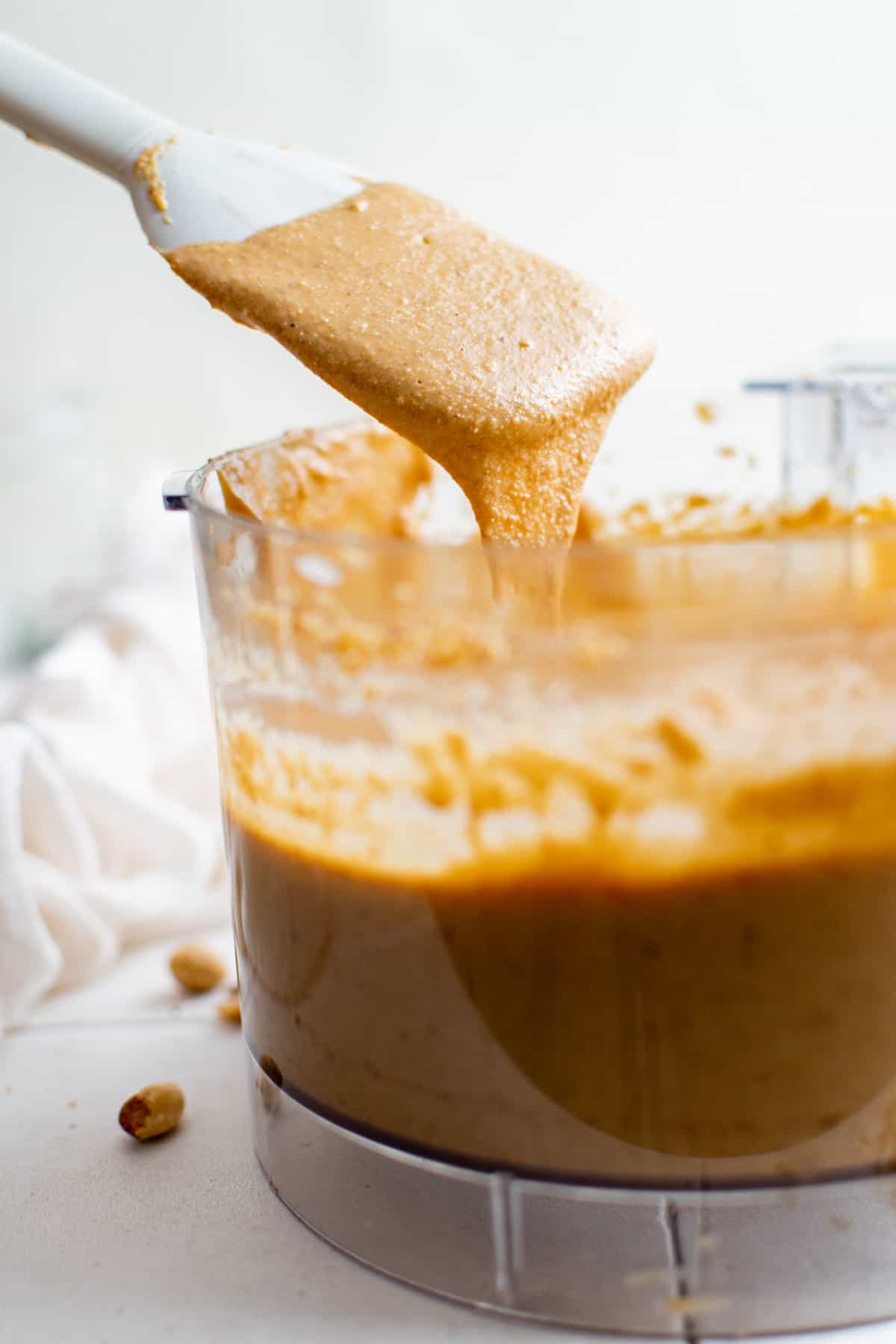 a spatula dipping into a food processor filled with peanut butter