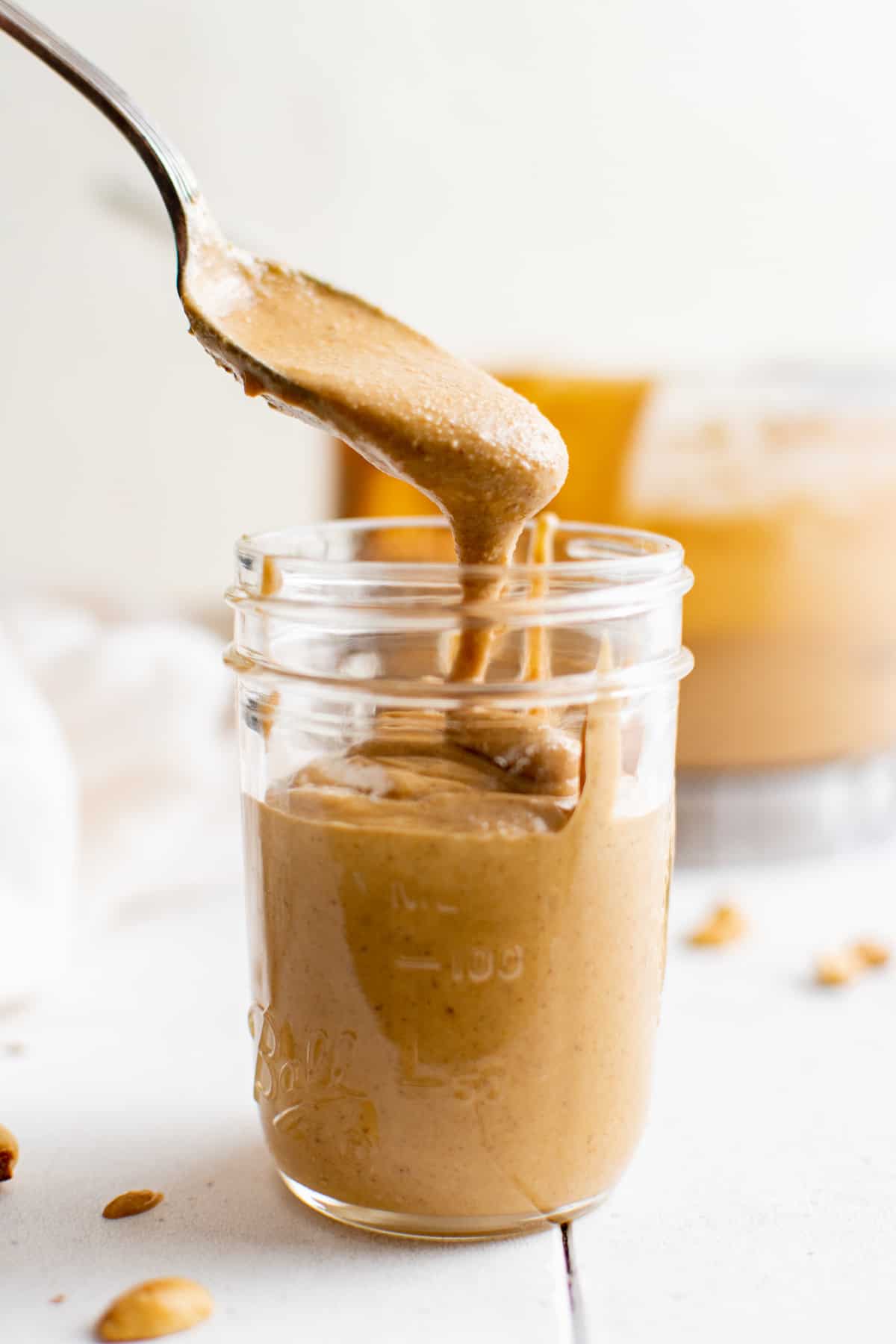 a spoon dipping into a jar of homemade peanut butter