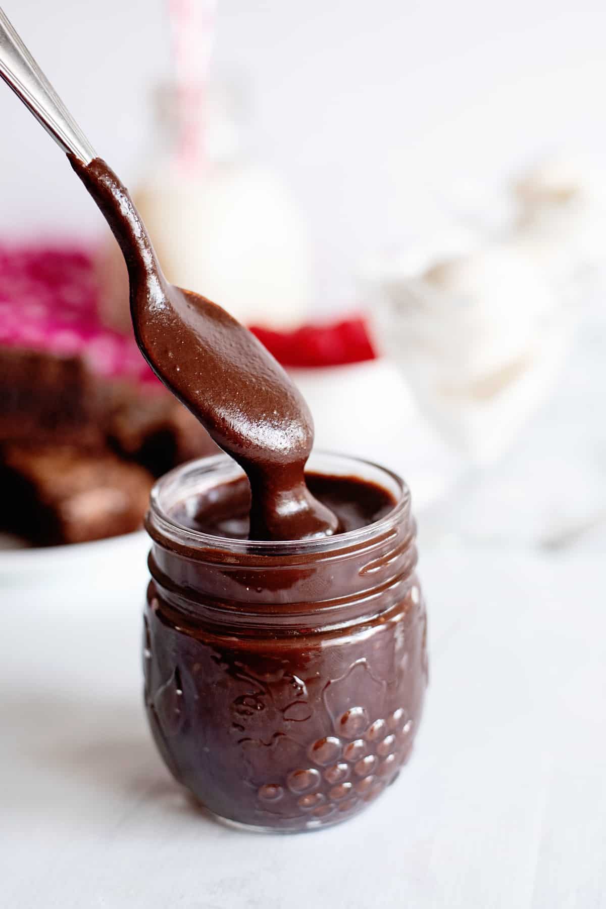 a spoon dipping into a jar of homemade hot fudge