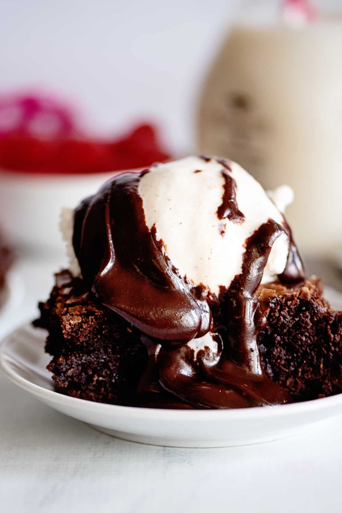 close up o a brownie topped with a scoop of ice cream and hot fudge sauce