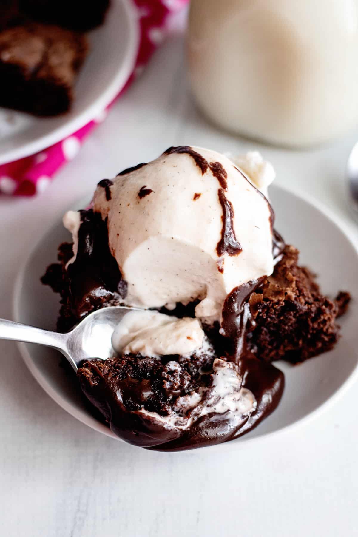 spoon scooping up a piece of brownie with ice cream and hot fudge
