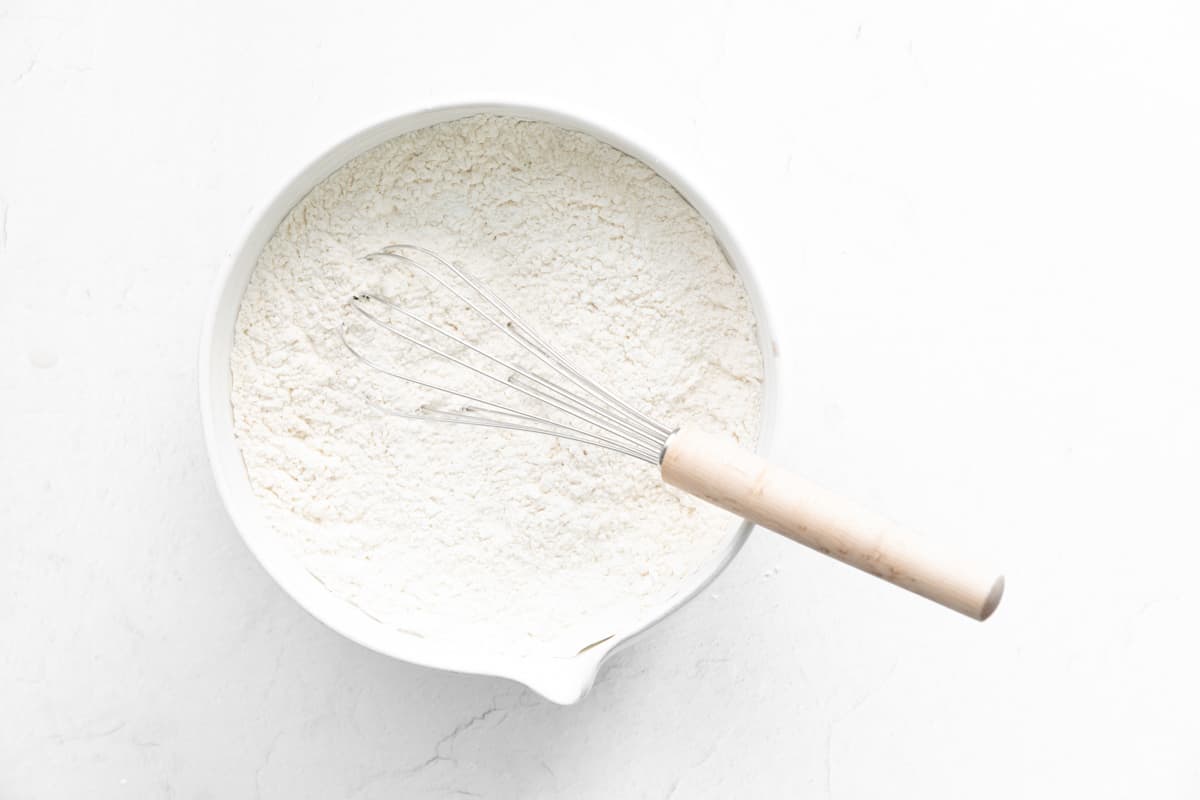 a whisk sitting in a bowl of flour