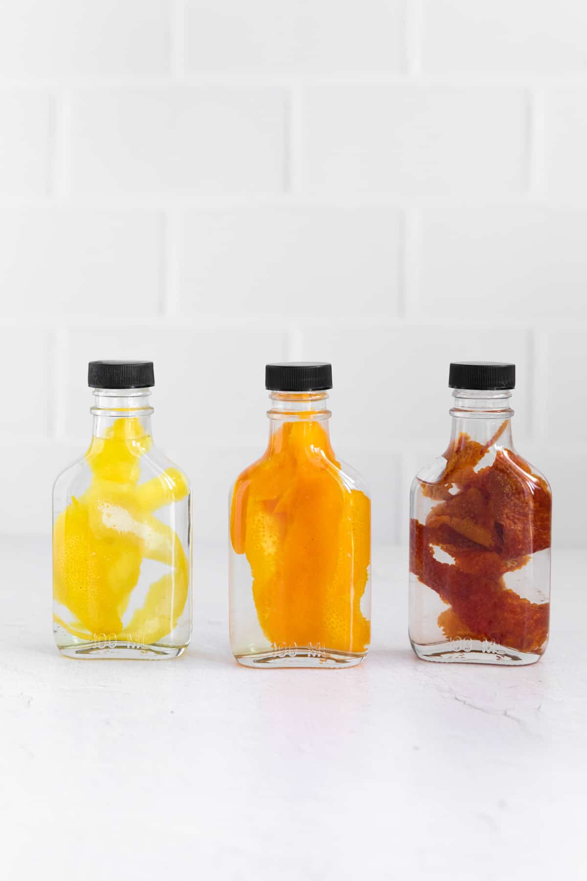 three clear bottles filled with homemade citrus extracts