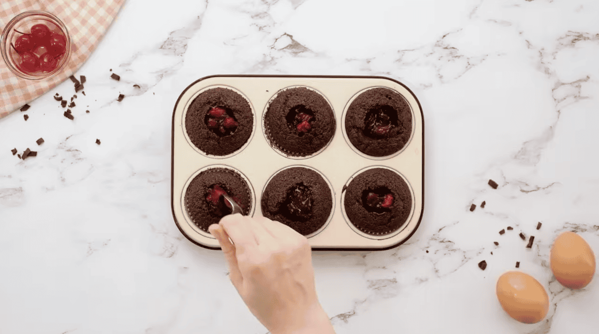 filling the scooped-out centers of chocolate cupcakes with cherry pie filling.
