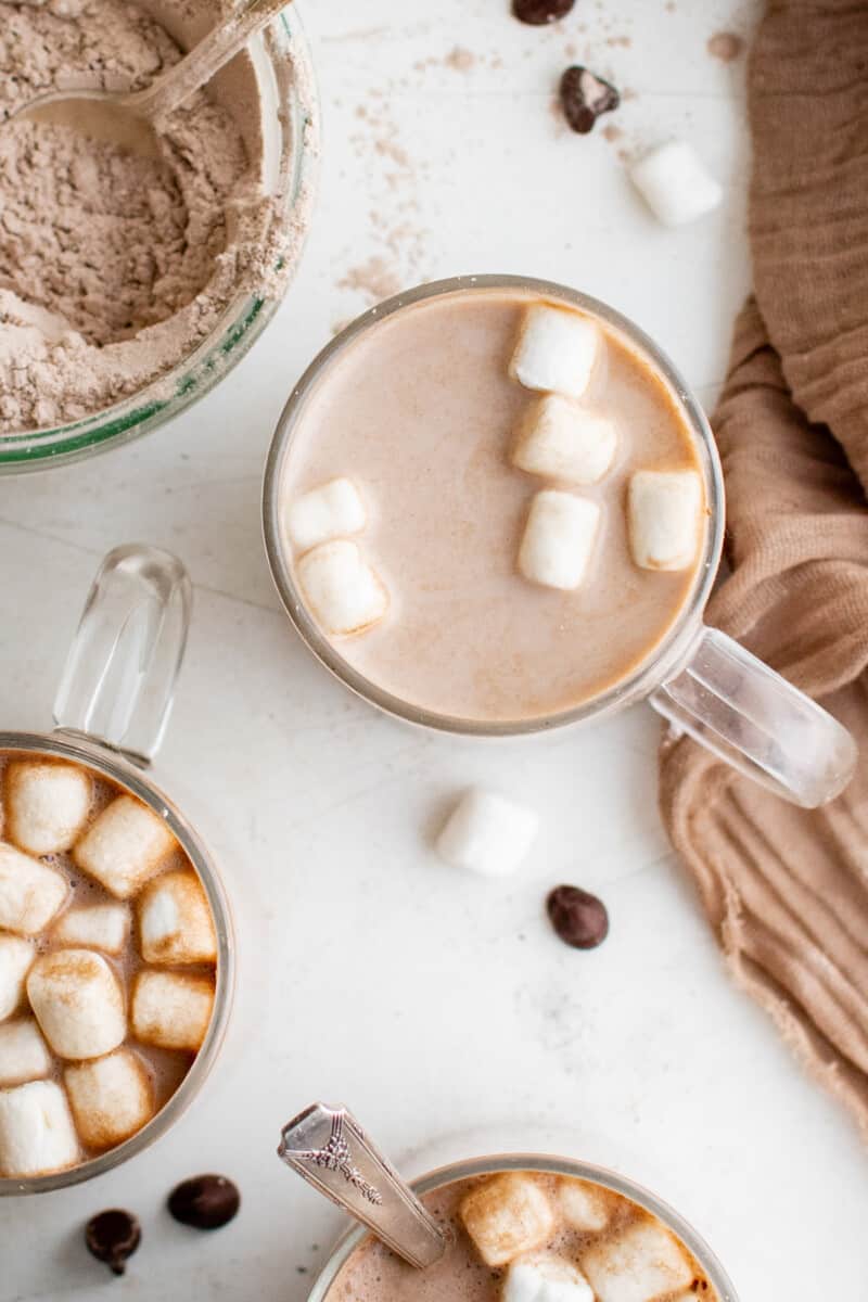 overhead view of prepared homemade hot chocolate in clear glass mugs with marshmallows.