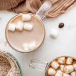 overhead view of prepared homemade hot chocolate in a glass mug with marshmallows.