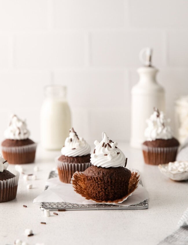 1 wrapped and 1 unwrapped hot chocolate cupcake on a wire rack.