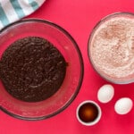 wet and dry ingredients for hot cocoa cookies in glass bowls next to eggs and vanilla extract.