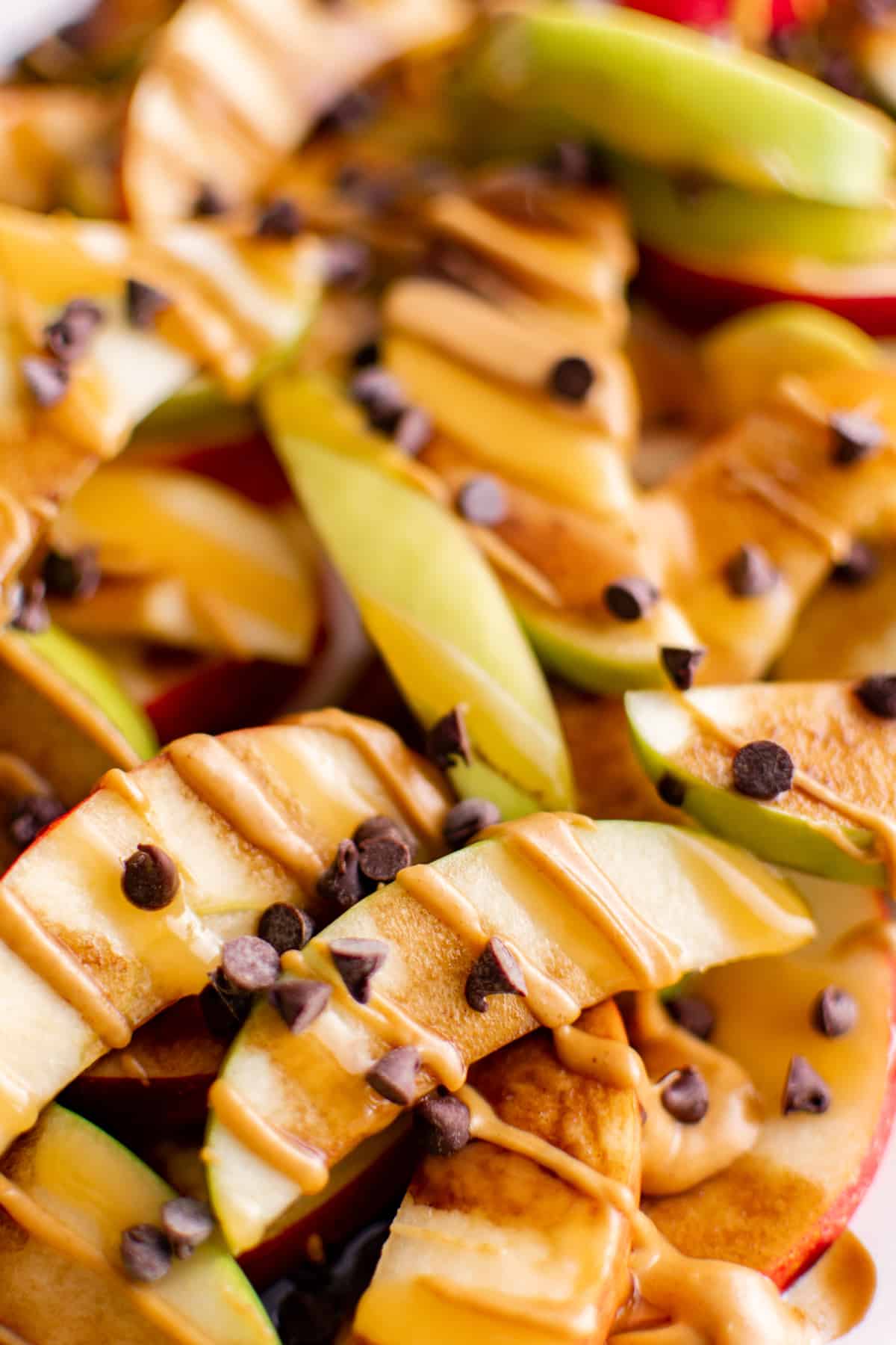 close up on apple nachos covered with peanut butter, caramel, and chocolate chips