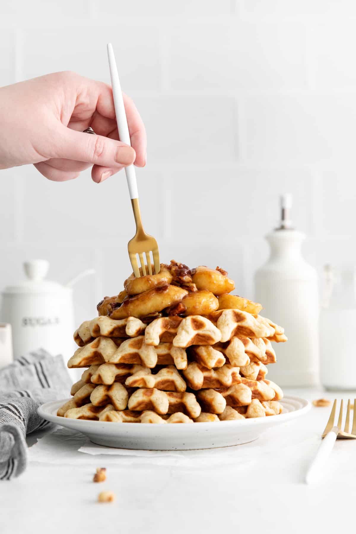 hand holding a fork as it pokes into the banana topping on the waffles