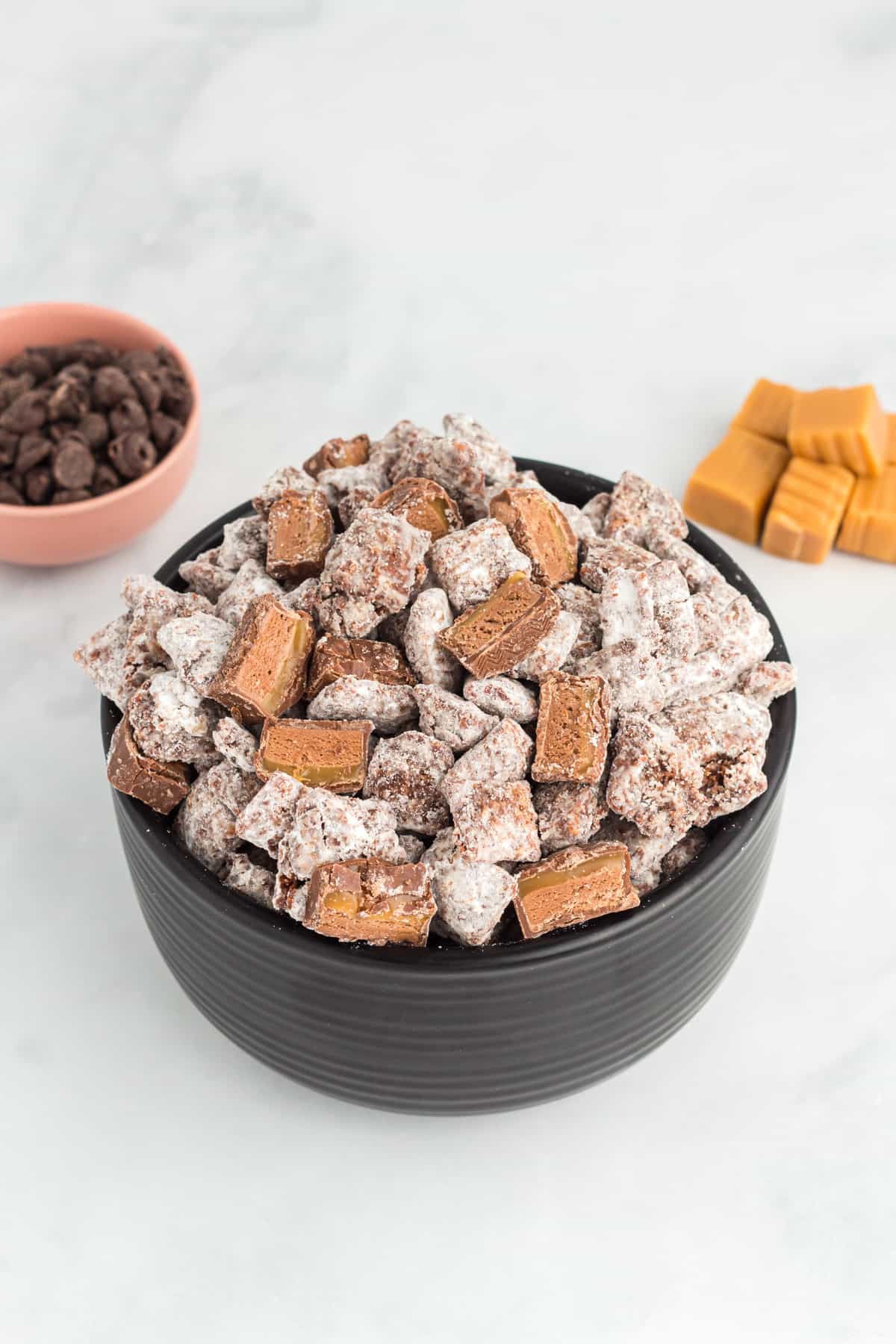 a bowl of puppy chow with chocolate caramel candies