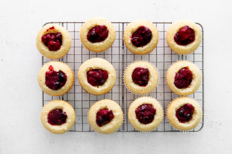 berry filled cupcakes on a cooling rack, with the center cut out