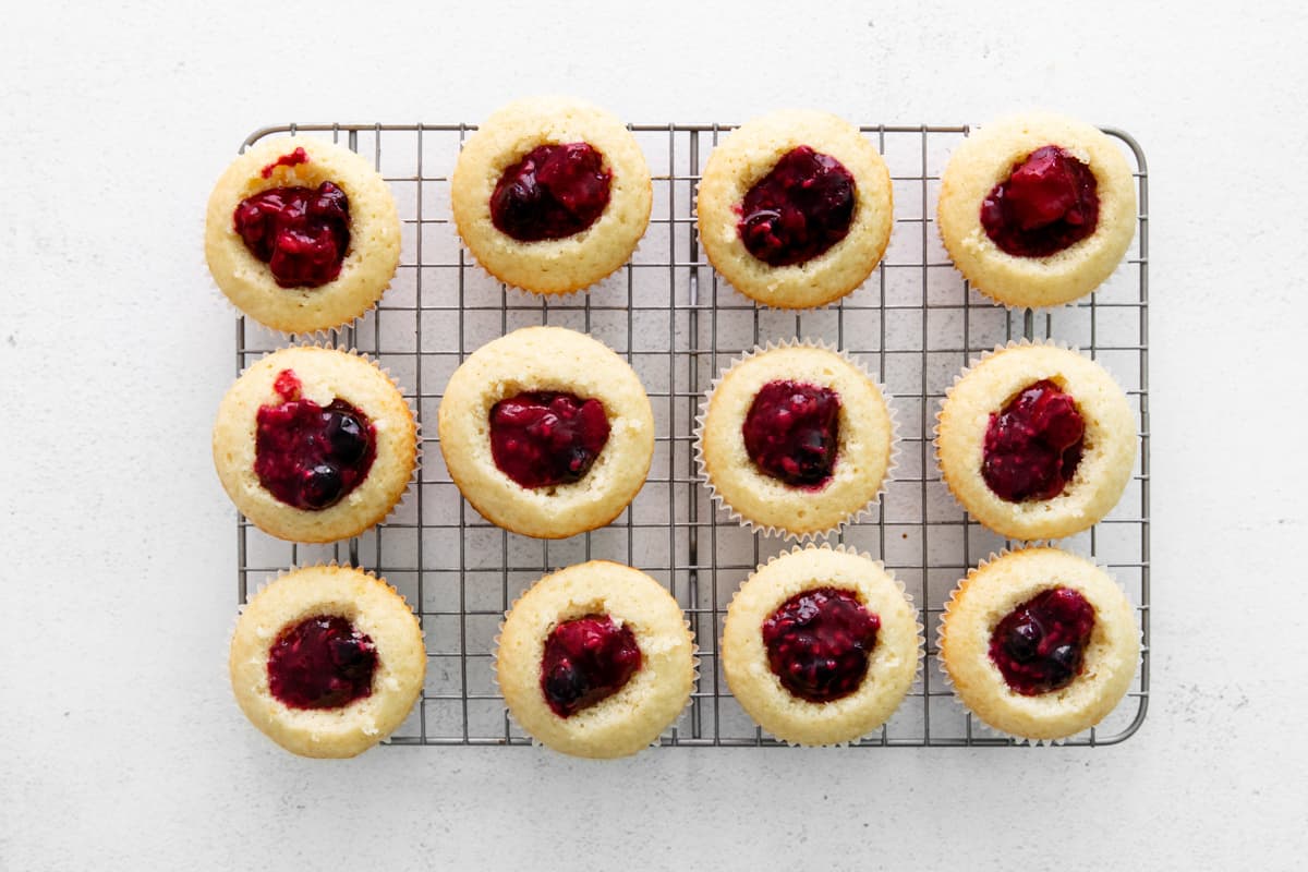 berry filled cupcakes on a cooling rack, with the center cut out