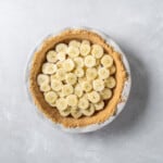 a pie with sliced bananas on a white surface.