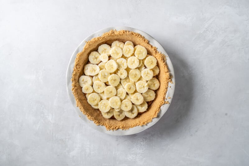 a pie with sliced bananas on a white surface.