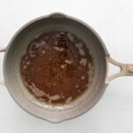 a brown sauce in a frying pan on a white background.