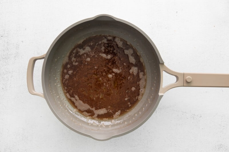 a brown sauce in a frying pan on a white background.