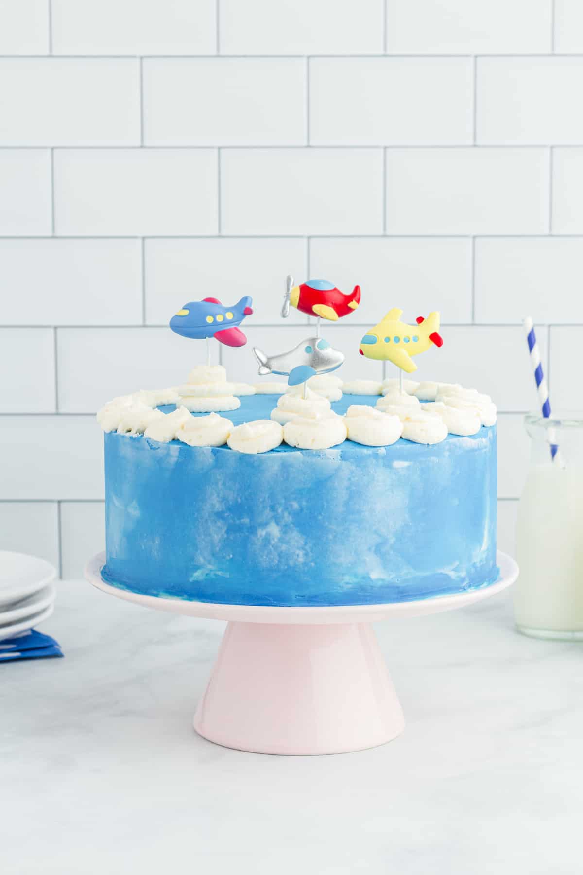 side view of airplane cake on a white cake stand.