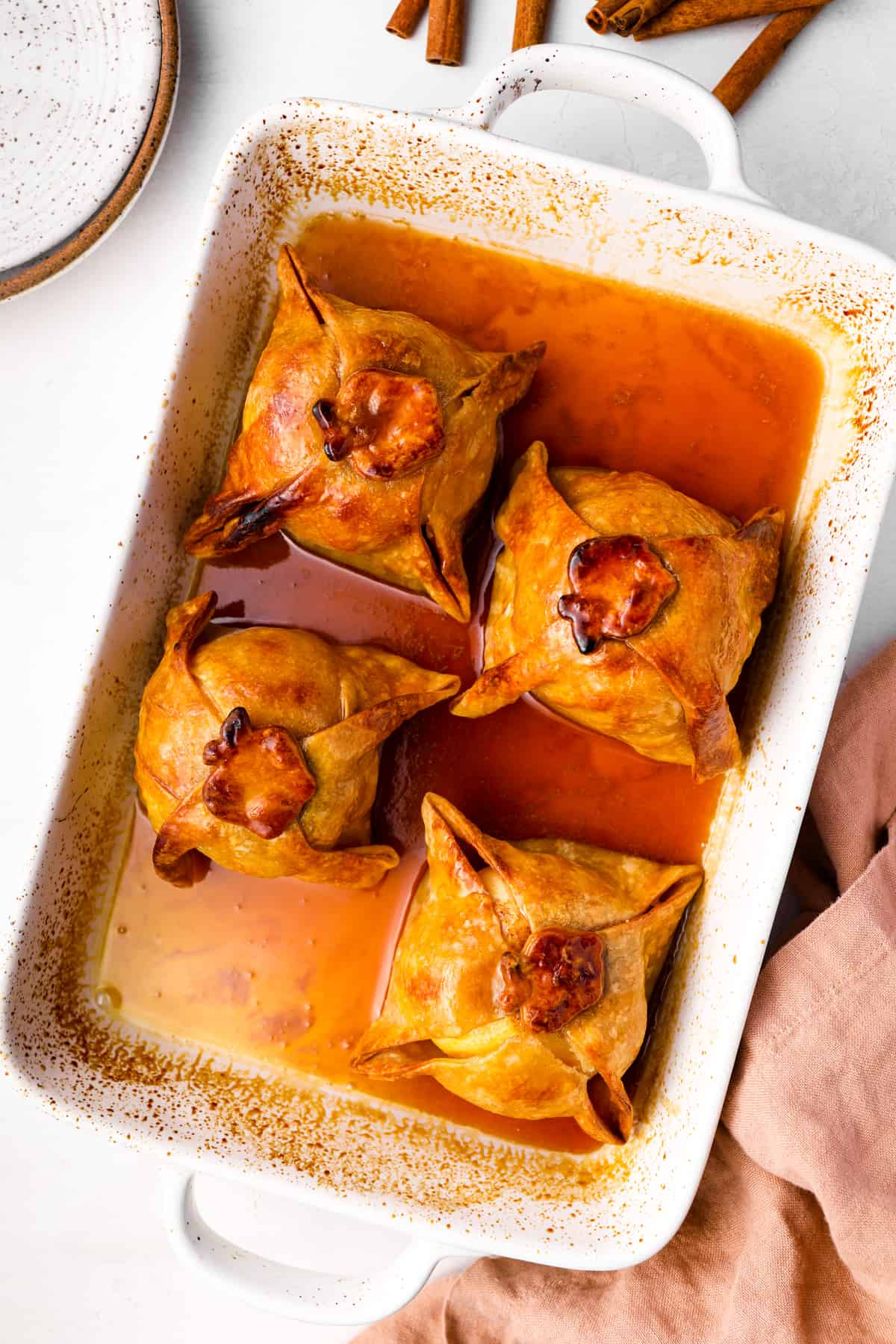 overhead view of 4 apple dumplings in a baking pan.