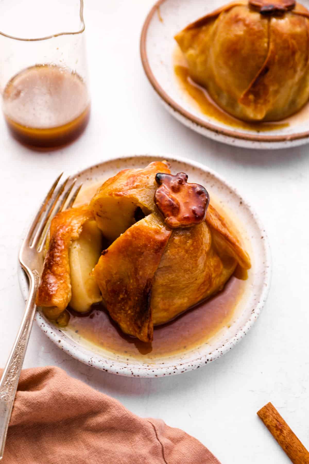 a cut apple dumpling on a white plate with a fork.