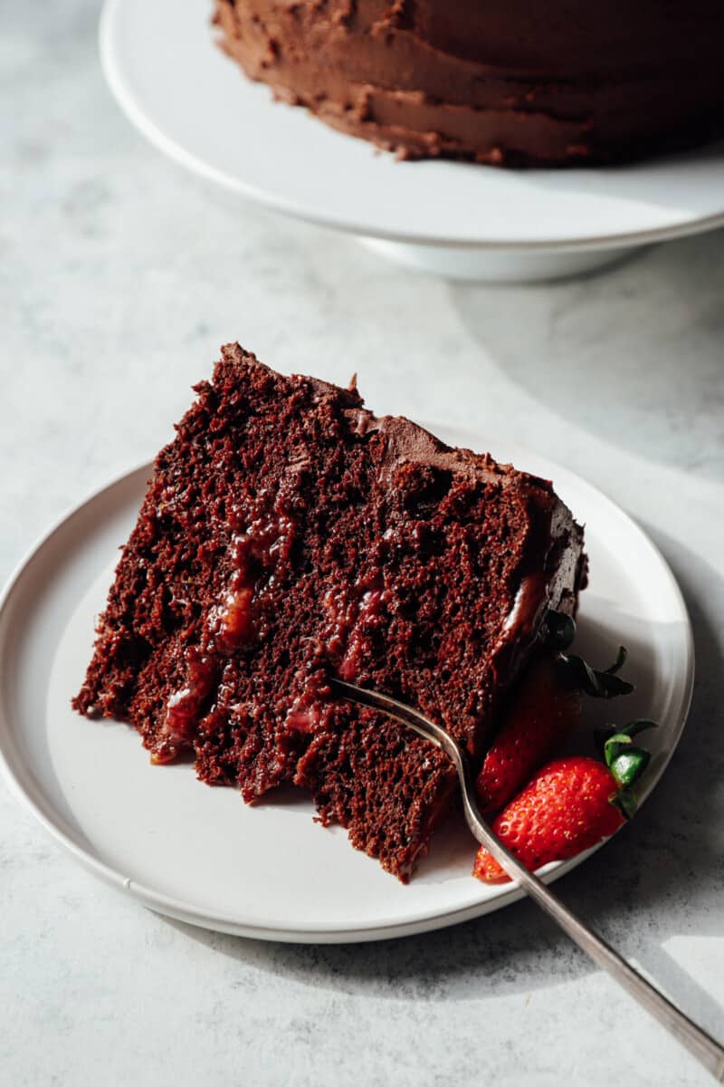 a slice of chocolate strawberry cake on a white plate with a fork.