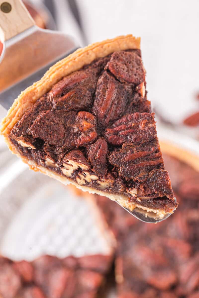 close up view of a slice of chocolate pecan pie on a pie server.