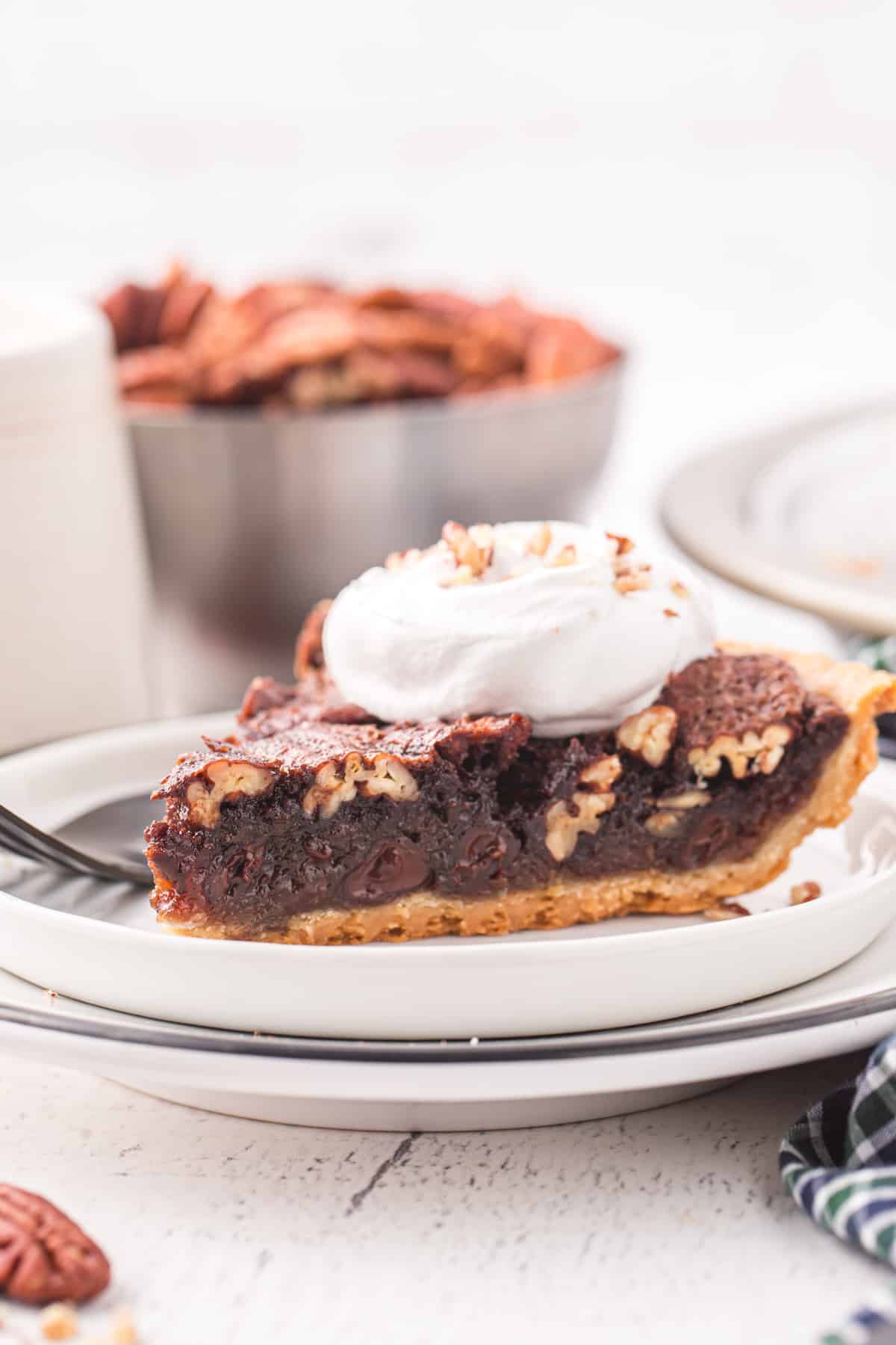 a slice of chocolate pecan pie on a white plate.